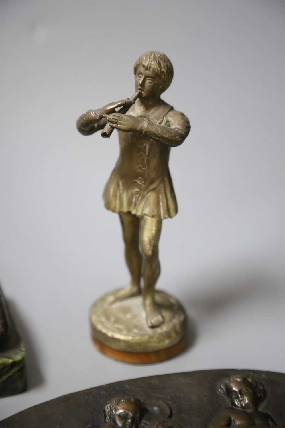 A bronze of a reclining female nude, a pair of plaques and a boy musician